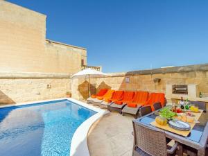 a swimming pool with chairs and a table next to a swimming pool at Traditional farmhouse with pool in Xagħra