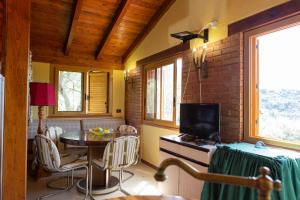 een woonkamer met een tafel en een televisie bij CHALET TRA GLI ULIVI: • giardino • WiFi • A/C • bbq in Capri Leone