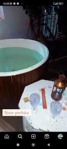 una bañera llena de agua verde junto a una mesa en Casa na Serra - em meio à um bosque c Ofurô aquecido en Jarinu