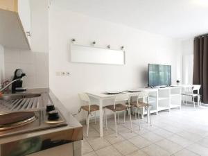 a white kitchen with a white table and chairs at Studio Zen hypercentre parking privé WIFI in Salon-de-Provence