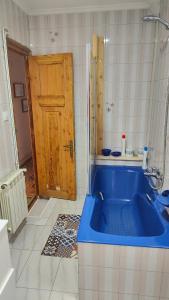 uma banheira azul numa casa de banho com uma porta de madeira em LAS LETRONAS em Gijón