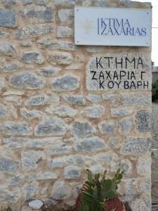 un mur en pierre avec un panneau sur un bâtiment dans l'établissement Ktima Zaxarias, à Kokkala