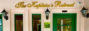 una señal en la parte delantera de un edificio con puertas verdes en The Kaptain's Retreat, en Chandīgarh