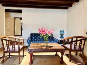 una sala de estar con un sofá azul y un jarrón de flores sobre una mesa en The Kaptain's Retreat, en Chandīgarh