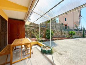 patio con tavolo in legno e tetto in vetro di WH - Bilocale Lamarmora con giardino a Sanremo