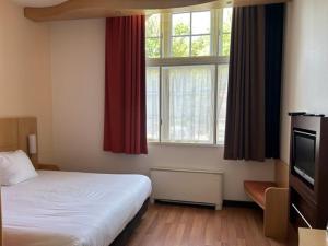 a bedroom with a bed and a large window at Onderwijshotel De Rooi Pannen Tilburg in Tilburg