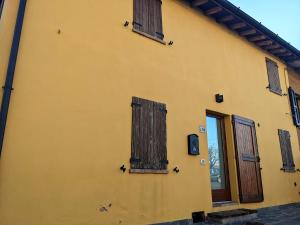 een geel gebouw met houten ramen aan de zijkant bij Casa Stella vicinanze Maranello in Casa Stella
