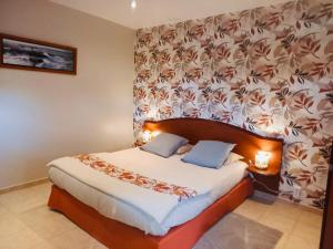 a bedroom with a large bed with a floral wallpaper at Maisonnette bretonne in Quemper-Guézennec