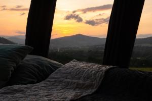 a bed in front of a window with a sunset at Kajuta in Betliar