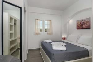 a white bedroom with a bed and a mirror at Sunset Village 6 in Paleochori