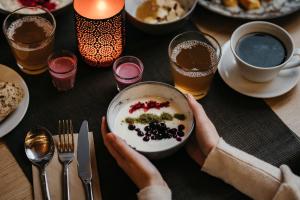 a person holding a bowl of food on a table at Lapland Hotels Ounasvaara Chalets in Rovaniemi