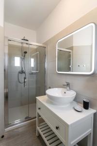 a white bathroom with a sink and a shower at Sunset Village 6 in Paleochori +8 photos
