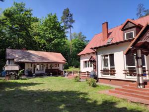 una casa con techo rojo y patio en Domek nad Poranną Rosą, en Garbatka-Letnisko