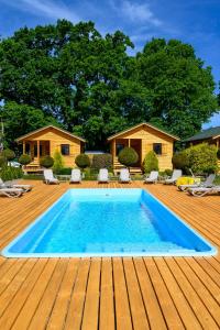 a swimming pool with a wooden deck and a house at Zielona Trawa in Bobolin