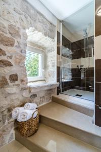 y baño con bañera y ducha con paredes de piedra. en Villa Nora - Charme Holidays, en Sutivan