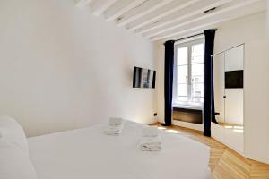 Pick A Flat's Apartment in Jardin du Luxembourg - Rue Royer Collard في باريس: غرفة نوم بيضاء مع سرير أبيض ونافذة