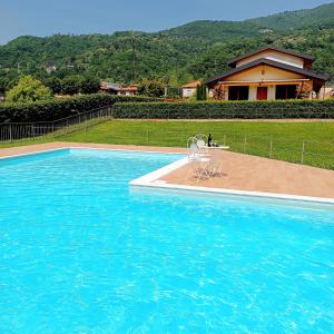 a blue swimming pool with a chair and a house at Casa Vacanze Alessandro in Spinone Al Lago