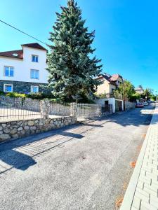 un arbre sur le côté d'une route avec une clôture dans l'établissement Svůj vlastní soukromý ráj-nájem apartmánu v Berouně!, à Beroun