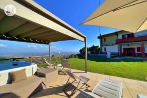 une terrasse avec des chaises, un bain à remous et un parasol dans l'établissement Agriturismo Irto Colle, à Massa e Cozzile