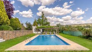 een zwembad in een tuin met een stenen muur bij Casa Los Morales Ronda by Ruralidays in Ronda
