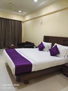 a bedroom with a large bed with purple pillows at UK's Resort in Talegaon Dābhāde