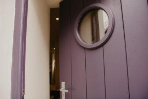 eine lila Tür mit einem runden Spiegel darauf in der Unterkunft The Old Brewery, Ulverston in Ulverston