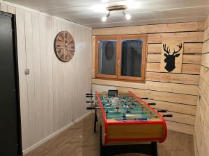 a room with a foosball table and a clock on the wall at Le chalet blanc de Gerardmer avec Spa in Gérardmer