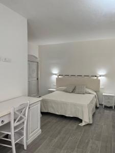 a white bedroom with a bed and a desk at Sa Jacca Albergo Rurale in Siniscola