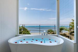 a bath tub in a bathroom with a view of the ocean at 海まで徒歩1分 沖縄でも珍しい絶景ホテル 贅沢プライベートビーチ付き ビーチルーム in Onna