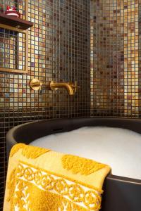 a bath tub with a yellow towel and a faucet at Upon Angels - Adults Only in Lisbon