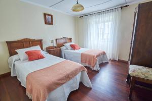 a hotel room with two beds and a window at Casa Choureiro Apartamentos Rurales in Navia