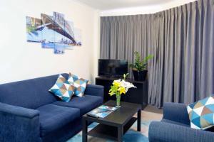 a living room with a blue couch and a tv at Metro Apartments on King in Sydney