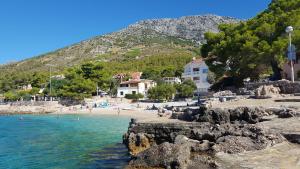 a beach with people in the water and a mountain at Seaside Stay Rošić 2 in Ivan Dolac