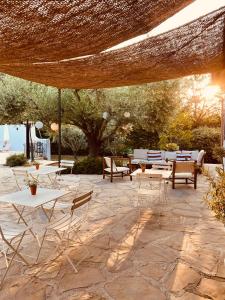 een patio met tafels en stoelen onder een rieten parasol bij 4 Saisons en Provence in Saint-Paul-en-Forêt
