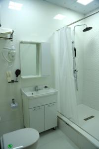 a white bathroom with a sink and a shower at Green Hotel Dushanbe in Dushanbe