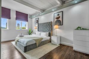 a bedroom with a large bed and two windows at 3 bed apartment near Old Street and City of London in London