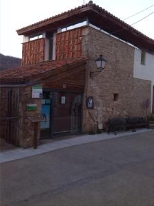 ein Steingebäude mit einer Tür und einer Bank davor in der Unterkunft Albergue Turístico Via de la Plata in Baños de Montemayor + 16 Fotos