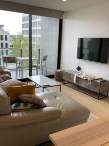 sala de estar con sofá y TV de pantalla plana en Lovely CBD two bedroom apartment free parking en Canberra