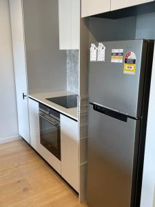 cocina con nevera de acero inoxidable y fogones en Lovely CBD two bedroom apartment free parking en Canberra