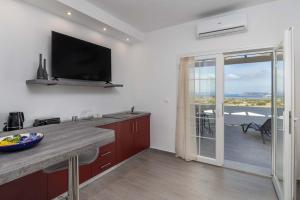 a kitchen with a flat screen tv on the wall at Sunset Village 1 in Paleochori +9 photos