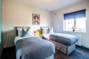 Cobden House - 5 Bed, 5 En-suite في Farnley: غرفة فندقية بسريرين ونافذة