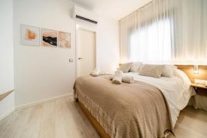 a white bedroom with a large bed with a window at TwinSuites Malaga in Málaga