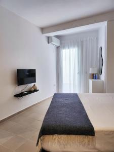 een slaapkamer met een bed en een tv aan de muur bij ELISOS Studio Apartment with swimming pool in Vlorë