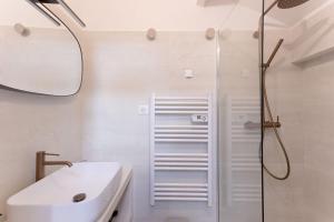 a white bathroom with a shower and a sink at Duplex Pradignac by Halldis in Cannes