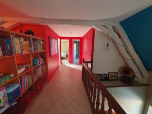 einen Flur mit roten Wänden und Bücherregalen in der Unterkunft La ferme du Riau in Aurouer