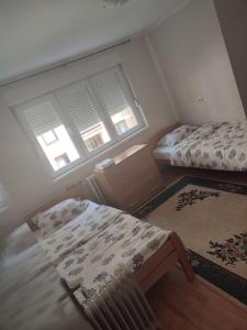 een slaapkamer met 2 bedden, een tafel en 2 ramen bij Apartman 1 in Foča