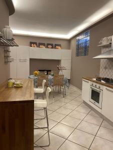 eine Küche mit weißen Schränken und einem Tisch mit Stühlen in der Unterkunft VERDESOLE HOUSE in Aci SantʼAntonio