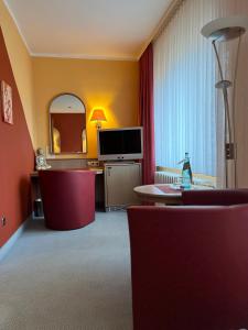 a hotel room with a tv and a mirror at Seehof Netzen in Lehnin