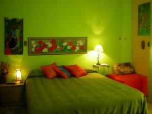 Dormitorio verde con cama con almohadas de color naranja en Orizzonte B&B, en Cefalú