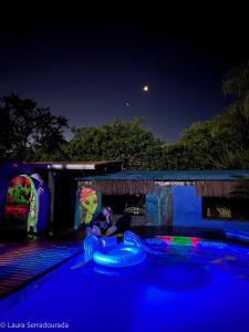 a person laying on a raft in a pool at night at Pousada Espaço Naves LunaZen in Alto Paraíso de Goiás